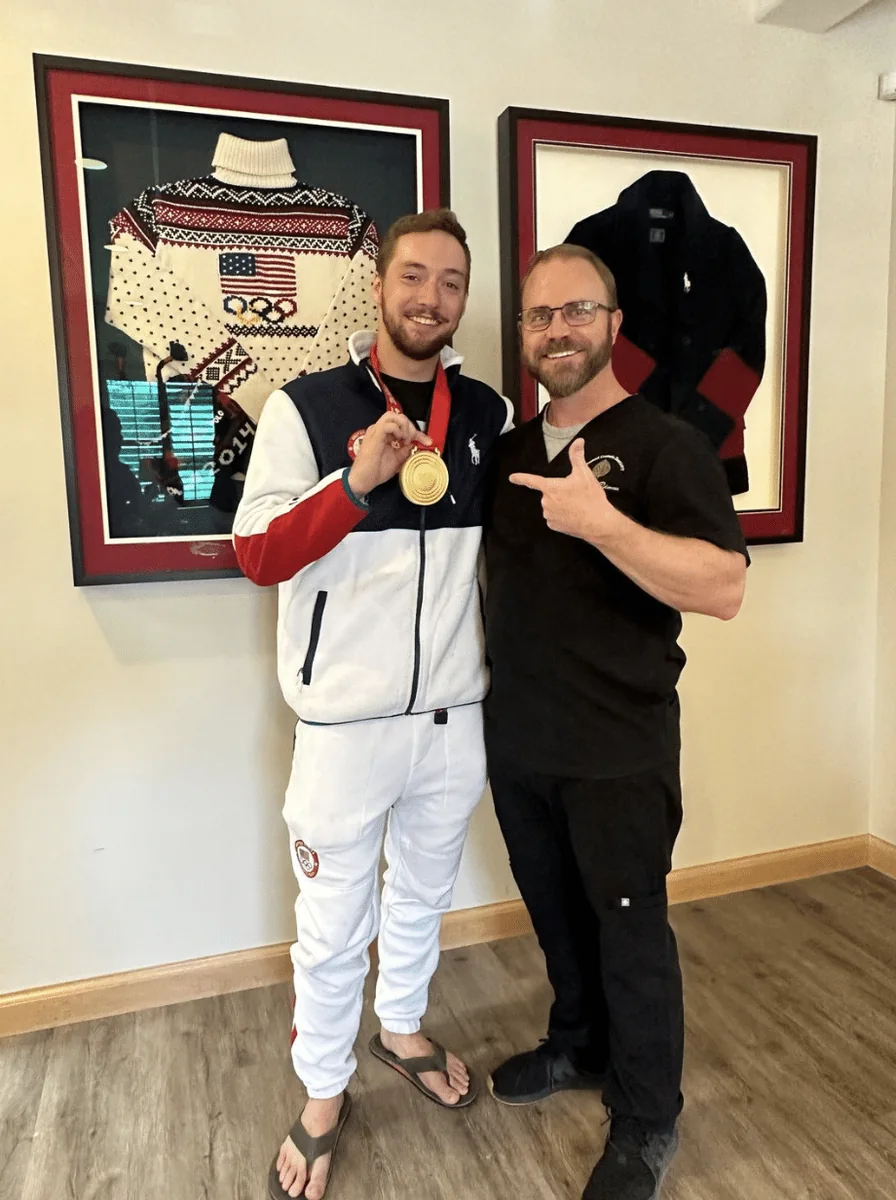 Chris Lillis holding an Olympic gold medal with Dr. Peterson